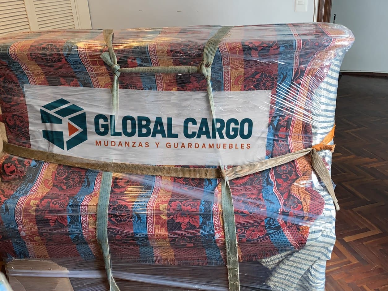 Mueble embalado con manta, film y cinchas, identificado con el logo de Global Cargo